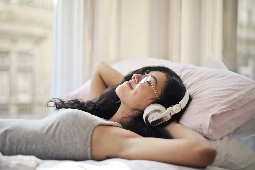 Mujer escucha musica en la cama